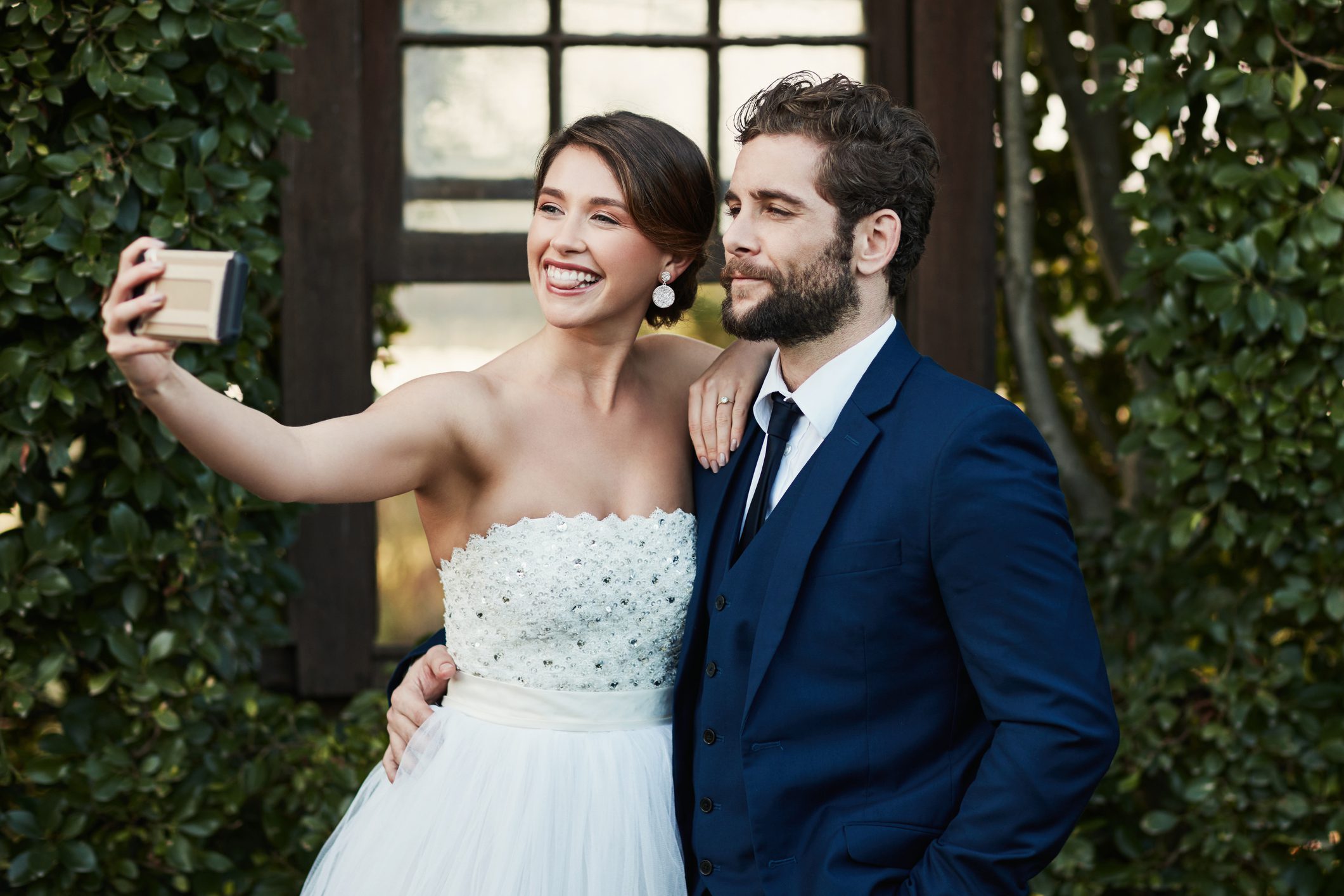 Bride and groom taking a selfie outdoors.