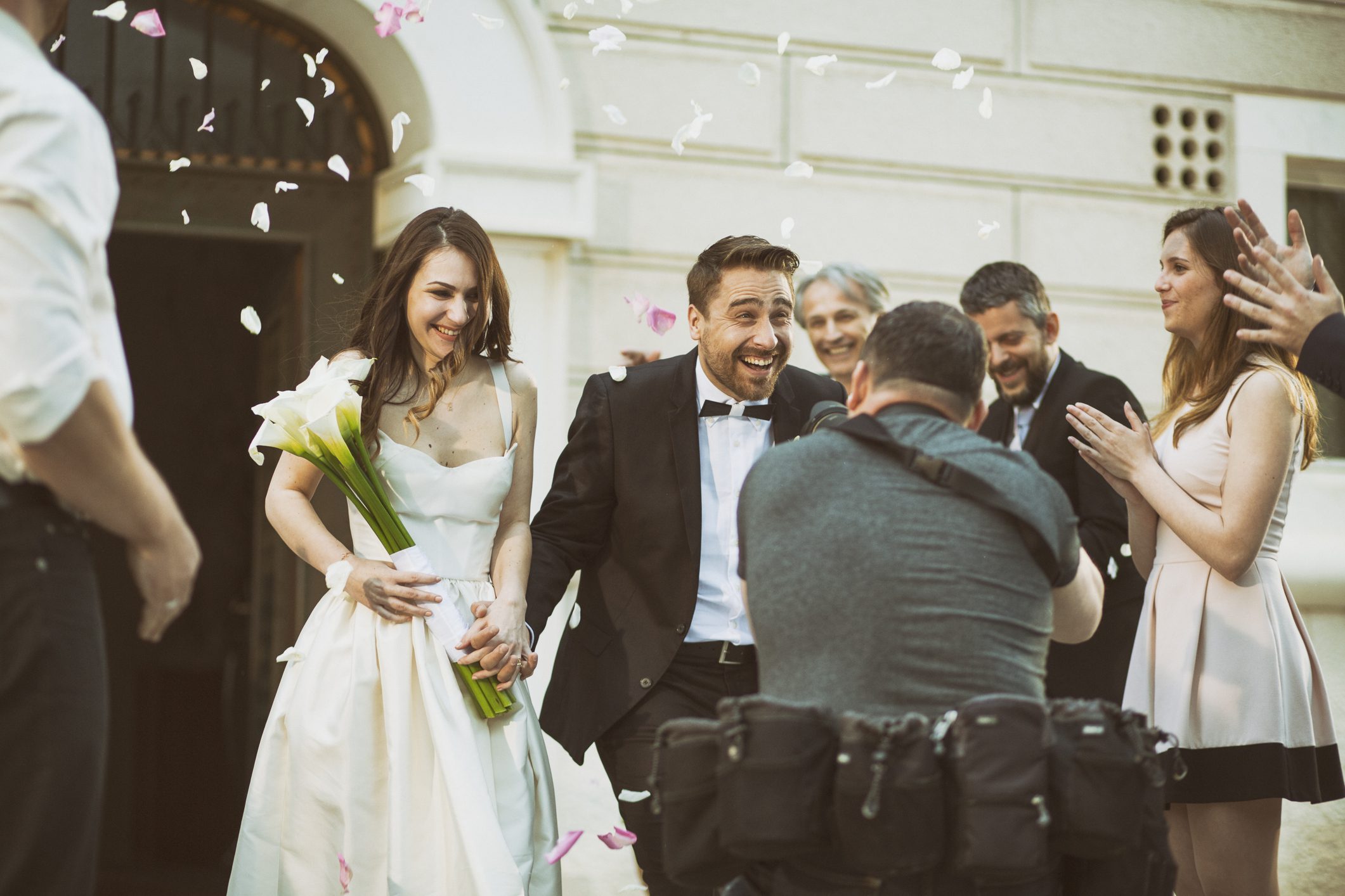 Wedding couple celebrating with guests outside venue.