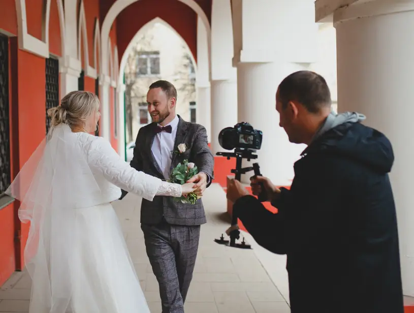 Bride and groom dancing, videographer recording moment.